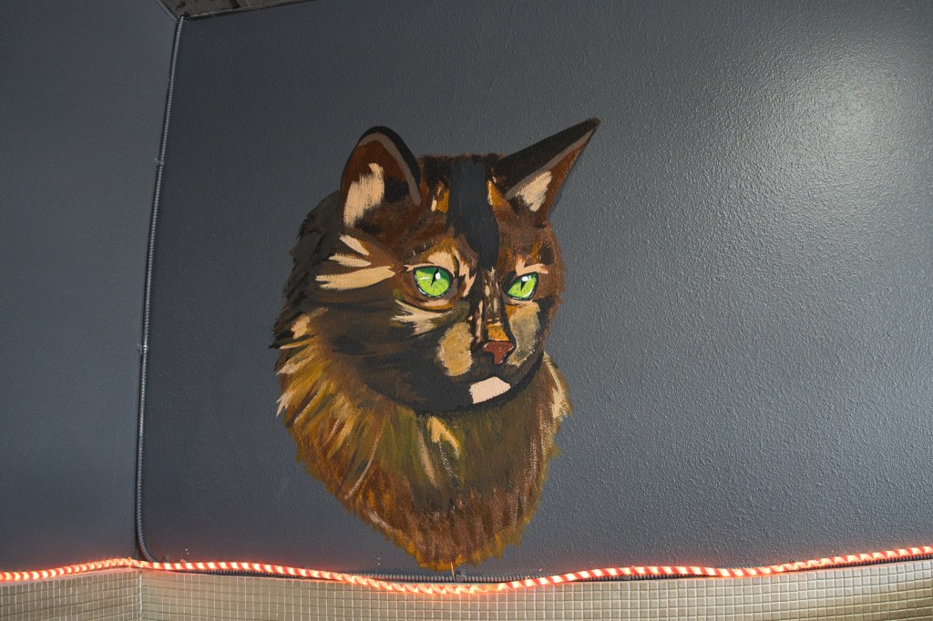 painting of a cat head on wall of cat cafe